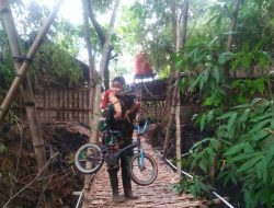 Babinsa Gapura, Bantu Anak Sekolah Menyeberangi di Jalan Longsor